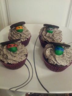 three cupcakes with frosting and decorations on them sitting on a white plate