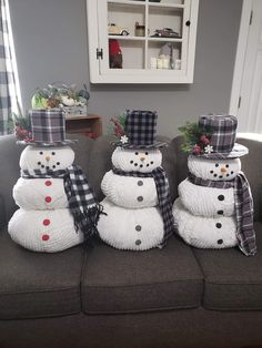 three snowmen are stacked on top of each other in front of a gray couch