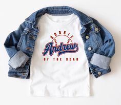 a white t - shirt with an image of a baseball on the back and blue jean jacket