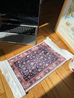 an old rug is laying on the floor next to a laptop