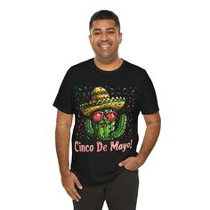 Jump into the festive spirit with our "Desert Fiesta" T-shirt! This vibrant tee captures the essence of Cinco de Mayo with a playful cactus character, decked out in a sombrero and cool shades, ready to party. Whether you're dancing at a fiesta or just bringing the party vibes to your everyday life, this t-shirt is the perfect way to celebrate the day. With a pop of color and a dash of Mexican flair, it's a wearable fiesta and a great conversation starter. Perfect for Cinco de Mayo or any day you want to celebrate life, this tee is a must-have for those who love to have fun with their style! This classic unisex jersey short sleeve tee fits like a well-loved favorite. Soft cotton and quality print make users fall in love with it over and over again. These t-shirts have-ribbed knit collars to Cinco De Mayo Screen Print Crew Neck T-shirt, Pre-shrunk Short Sleeve T-shirt For Cinco De Mayo, Cinco De Mayo Graphic Tee With Short Sleeves, Cinco De Mayo Graphic T-shirt, Cinco De Mayo Graphic Cotton T-shirt, Cotton Graphic Tee For Cinco De Mayo, Black Crew Neck T-shirt For Cinco De Mayo, Cinco De Mayo Graphic Print T-shirt, Cinco De Mayo Funny Print Crew Neck T-shirt