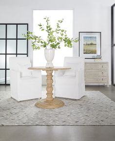 a living room with white chairs and a round table in the middle of the room