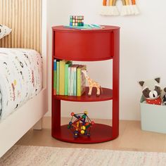 a red shelf with books and toys on it in a child's room next to a bed