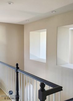 two empty square windows are on the wall in an empty room with white railings