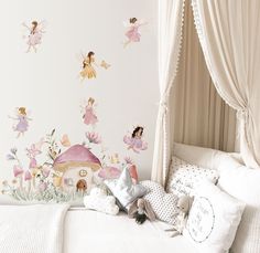 a white bed topped with lots of pillows next to a wall covered in fairy decorations