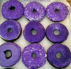 purple donuts with sprinkles are in a box