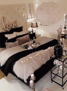 a bedroom decorated in black and white with lights on the headboard, bedding, and pillows