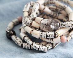 a close up of a bracelet made out of old book pages with beads on it