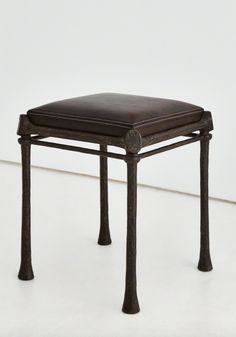 a brown leather stool sitting on top of a white floor