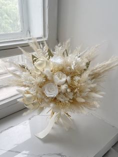 a bouquet of white flowers sitting on top of a window sill next to a window