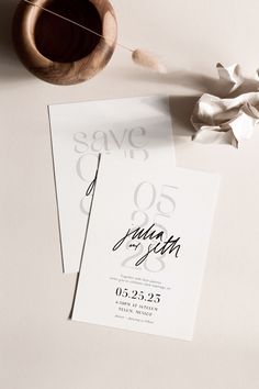 the wedding stationery is laid out next to a wooden bowl and white paper with black ink