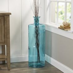 a blue vase with branches in it sitting next to a wooden table and window sill