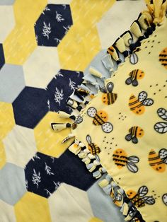 a yellow and blue quilt with bees on it's side, next to a black and white checkered table cloth