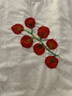 four red flowers are embroidered onto a white t - shirt with green stems on it