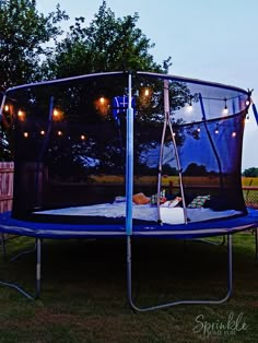 a blue trampoline with lights hanging from it's sides