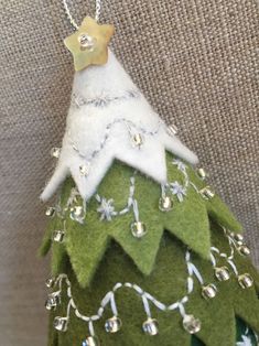 a green christmas tree ornament hanging from a chain on a fabric wallpaper