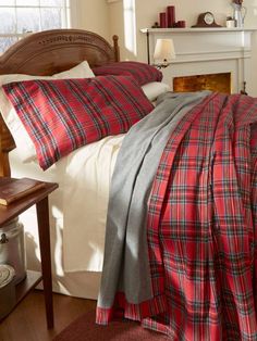 a bed with red and grey plaid comforter, pillows and blankets on top of it