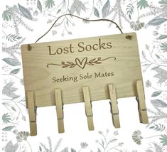 a wooden sign that says lost socks seeking sole mates hanging on a wall with flowers in the background