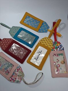 several small purses are lined up on a white surface with tags attached to them