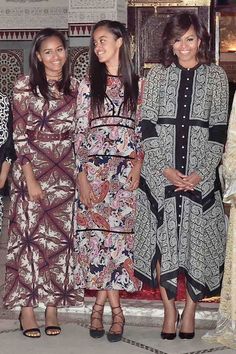 four women standing next to each other in dresses