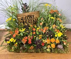 a wooden sign sitting on top of a table filled with flowers and plants in front of it