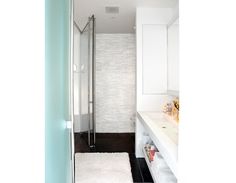 a bathroom with white walls and black flooring, including a shower stall in the corner