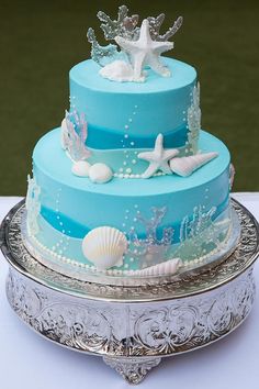 a three tiered cake with blue frosting and seashells