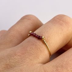 This beautifully simple ring is lovingly handmade with 5 tiny Garnet gemstones and a choice of 14k Gold Filled, 14k Rose Gold Filled or Sterling Silver band. M A T E R I A L S: * Garnet * 14k Gold Filled, 14k Rose Gold Filled or Sterling Silver S I Z E: *  Gemstone - Approximately 2mm each *  Band Thickness - Approximately 0.8-1mm  All of our jewellery is carefully handmade using good quality materials and handpicked gemstones, with the aim to produce quality pieces that you can love & wear for Handmade Minimalist Adjustable Birthstone Ring, Handmade Adjustable Minimalist Birthstone Ring, Dainty Adjustable Ruby Ring Gift, Adjustable 14k Gold Ruby Ring For Anniversary, Dainty Adjustable Ruby Ring For Anniversary, Minimalist Adjustable Ruby Promise Ring, Minimalist 14k Gold Wire Wrapped Rings, Dainty Yellow Gold Wire Wrapped Rings, Adjustable 14k Gold Midi Rings With Birthstone