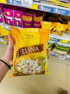 a hand holding a bag of fellina rice in front of a store shelf