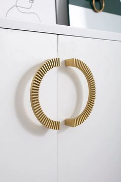 a close up of a metal object on a white cabinet with a gold ring attached to it