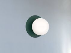 a white ball hanging from the side of a gray wall next to a green circle