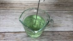 a green liquid in a glass cup with a metal straw sticking out of the top