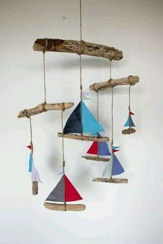 a wind chime made out of driftwood with colorful sailboats hanging from it