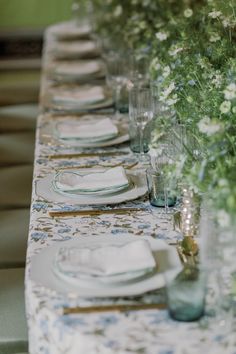 a long table is set with plates and flowers