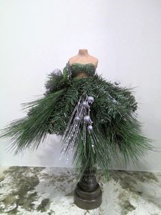 a mannequin wearing a green dress made out of pine needles and tinsel