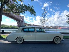 an old white car parked in front of a bridge