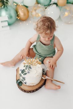 a baby sitting on the floor with a cake