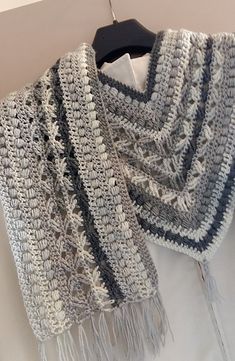 a crocheted shawl is hanging on a hanger