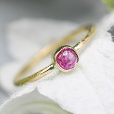 "\"Square Pink Sapphire Ring with 18k Gold Texture Band\" Gemstone: Pink Sapphire: This exquisite ring features a captivating square pink sapphire, securely set in a bezel setting. The pink sapphire measures 3.9mm in width and 3.6mm in height, showcasing a delicate and enchanting pink hue. Band Material: The band of this elegant ring is expertly crafted from 18k yellow gold and features a slender width of 1mm. Band Texture: The 18k gold band exhibits intricate texturing, adding a unique and artisanal touch to the overall design. Resizing: This ring offers the convenience of free resizing, ensuring it fits comfortably and perfectly on your finger. Specifications: Ring Style: Square Pink Sapphire Ring with 18k Gold Texture Band Gemstone: Pink Sapphire Setting: Bezel Band Material: 18k Yellow Pink Sapphire Cushion Cut Ring For Gift, Cushion Cut Pink Sapphire Ring Gift, Cushion Cut Pink Sapphire Rings, Pink Sapphire Stackable Ring Gift, Fine Jewelry Pink Ring With Bezel Setting, Yellow Gold Pink Sapphire Gemstone Ring, Pink Stackable Sapphire Ring Gift, Fine Jewelry Pink Sapphire Stackable Rings, Pink Sapphire Stackable Rings Fine Jewelry