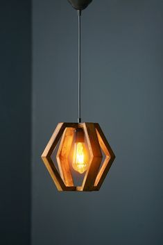 a wooden light fixture hanging from a ceiling in a room with dark walls and grey walls