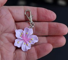 a hand holding a flower shaped keychain in it's palm