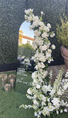 white flowers are placed in front of a mirror on the ground with a planter behind it