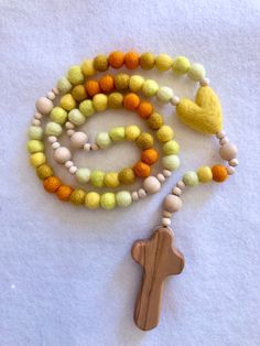 This soft, beautiful rosary makes the perfect gift for any occasion. Carefully crafted with highest quality materials. Beads are made of 100% sheep's wool and natural wood with a silky smooth olive wood cross from the Holy Land.   Hail Mary Wool Beads: 1 cm diameter Our Father Wood Beads: 12 mm diameter Small Wood Spacer Beads: 6 mm diameter Olive Wood Cross: Approximately 6cm long and 3 cm wide Total Length when laid flat: approximately 18 inches White Wooden Beads Rosary As Gift, White Rosary With Wooden Beads As Gift, Handmade Cross Rosary For Blessings, Yellow Spiritual Rosary As Gift, Handmade Rosary With Round Beads For Baptism, Handmade Cross Rosary For First Communion, Handmade Adjustable Rosary For First Communion, Spiritual 8mm Beads Rosary For Baptism, Beautiful Rosary