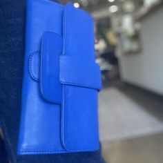 In-house design that came to life through fair trade artisans in Indonesia. Leather wallet with belted closure in blue. Perfect as a wallet, and for a clutch with a pop of color. 9" L x 5" W, tri-fold wallet with snap closure and asthetic buckle. Interior: 19 card slots, large zipper pocket, 3 large slide pockets. Modern Blue Leather Clutch, Blue Rectangular Wallet For Everyday Use, Rectangular Blue Wallet For Everyday Use, Blue Rectangular Wallet With Cell Phone Pocket, Versatile Blue Wallets For Everyday Use, Travel Wallet With Cell Phone Pocket In Blue, Blue Everyday Rectangular Wallet, Everyday Blue Rectangular Clutch, Blue Wallets With Interior Card Slots For Daily Use