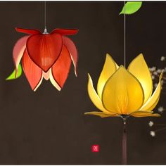 two paper flowers hanging from strings in front of a dark background