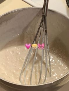 the whisk is being stirred by two pink bow - shaped candy lollipops