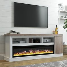 an entertainment center with a flat screen tv mounted on it's wall and fire in the fireplace