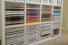 a book shelf filled with lots of different colored books on top of carpeted floor