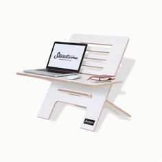 a laptop computer sitting on top of a white chair with a wooden frame and legs