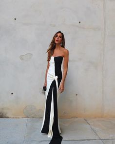 a woman in a black and white dress posing for the camera with her hand on her hip